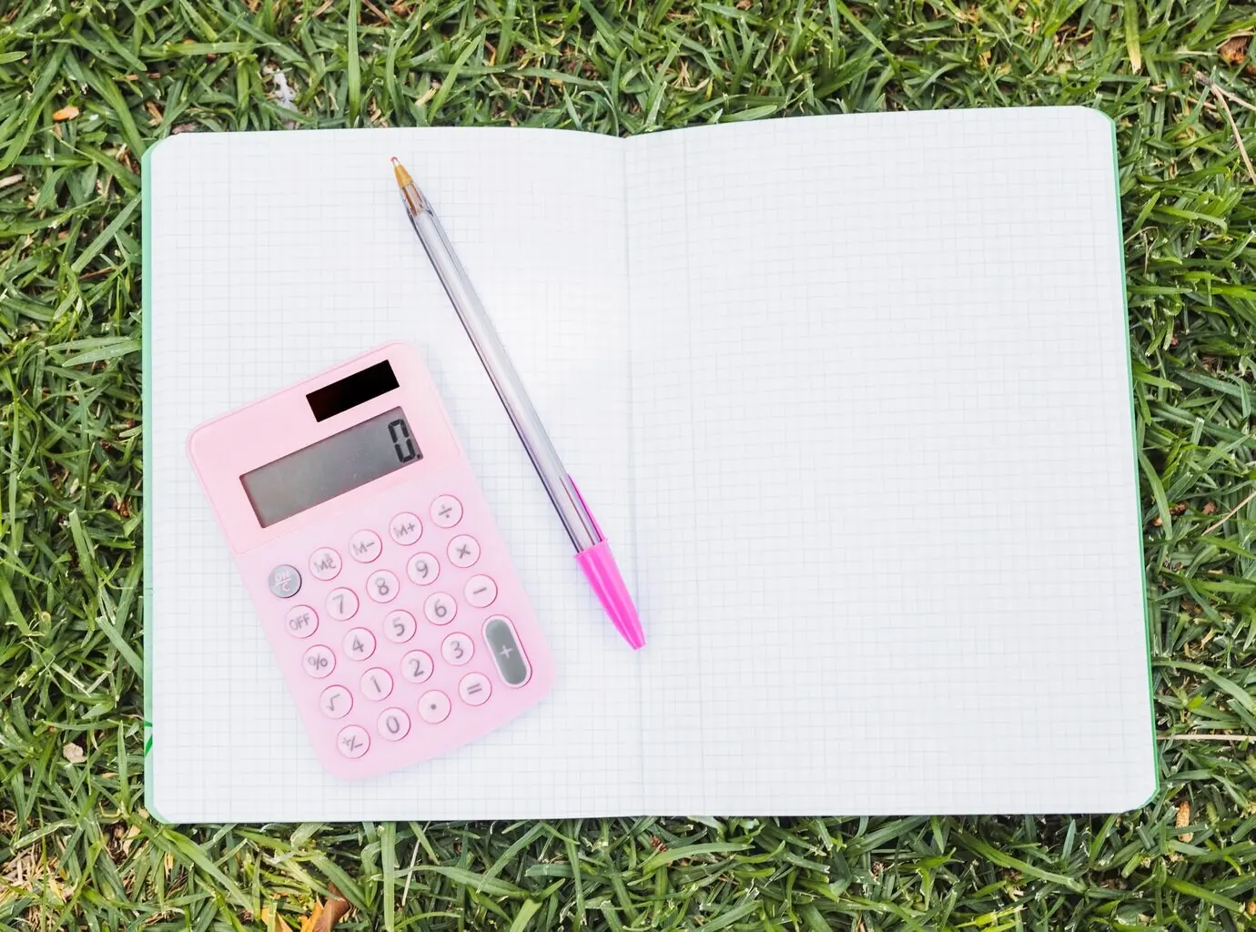 A calculator and a pen resting on an open notebook.
