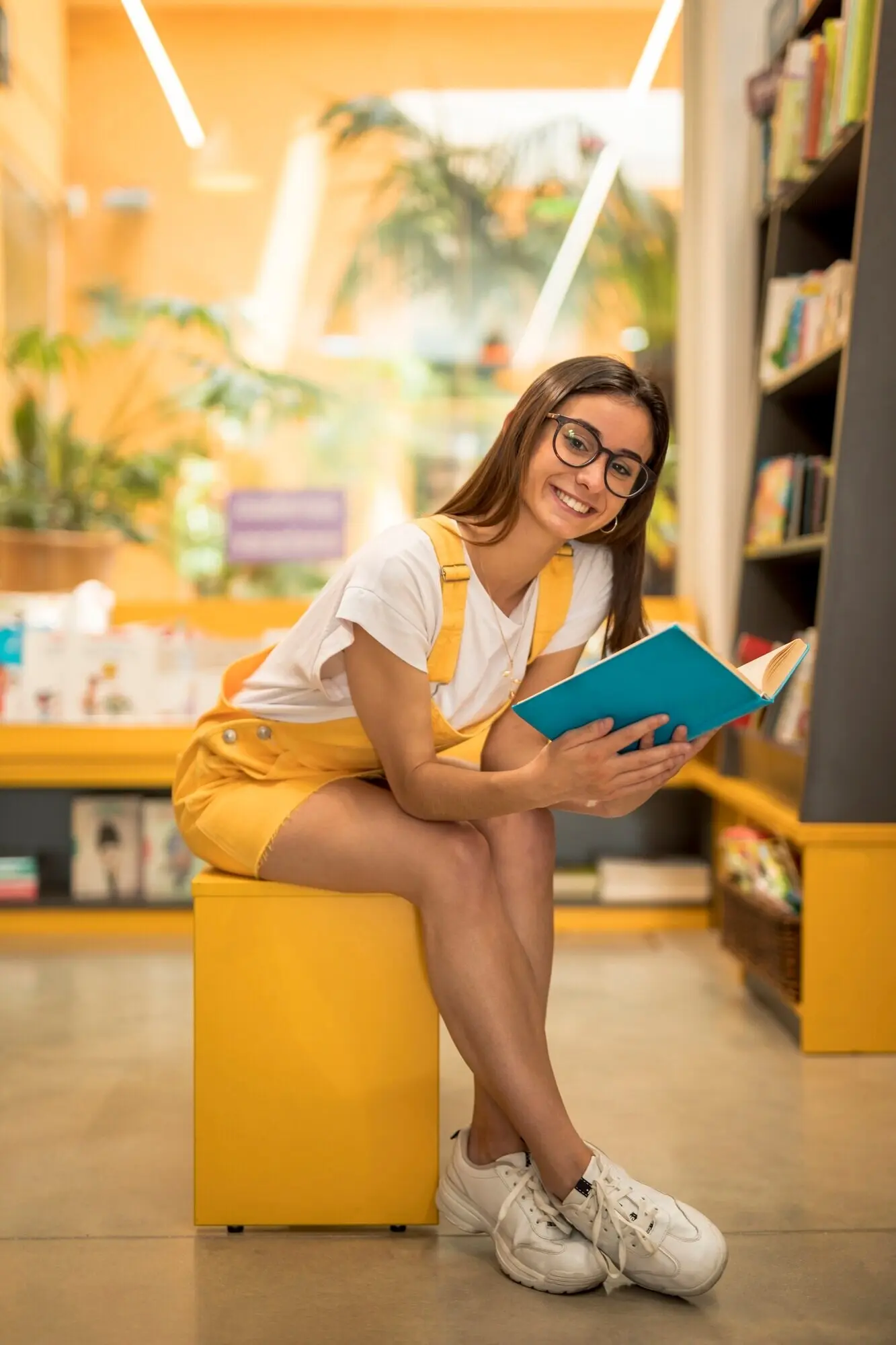 A teenage schoolgirl sits on a bench with a book.