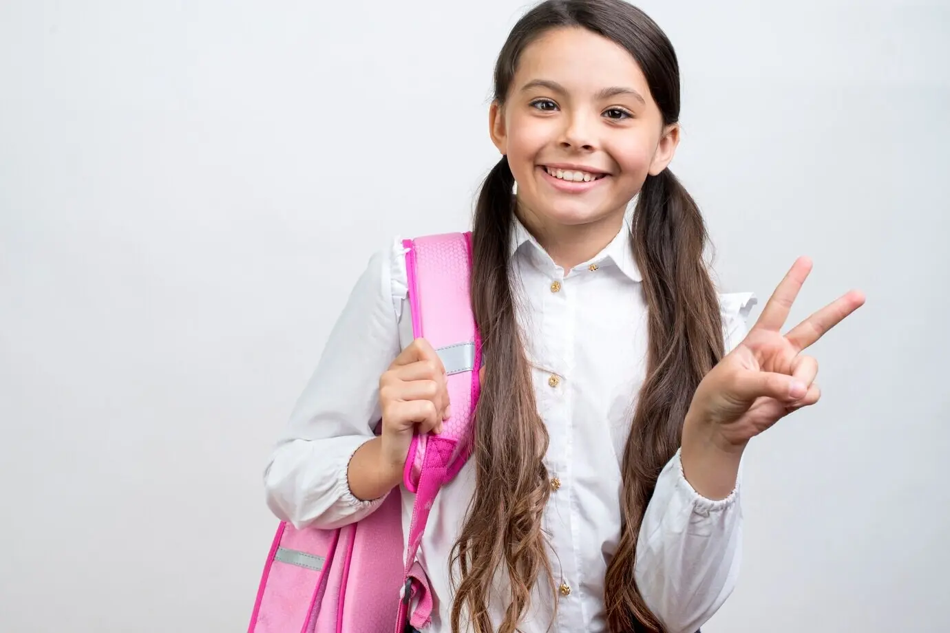 Playful Hispanic schoolgirl with a backpack on her shoulder